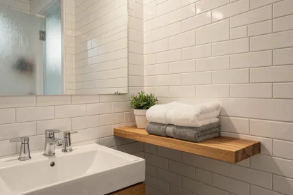 Salle de bain moderne propre et bien organisée avec des serviettes pliées et des surfaces en carrelage blanc immaculé